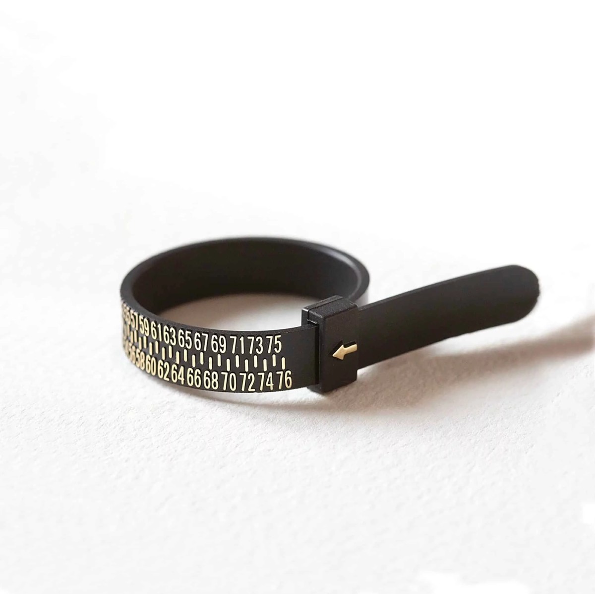 Baguier noir réglable avec chiffres gradués utilisé pour mesurer la circonférence du doigt et déterminer la taille de bague exacte.